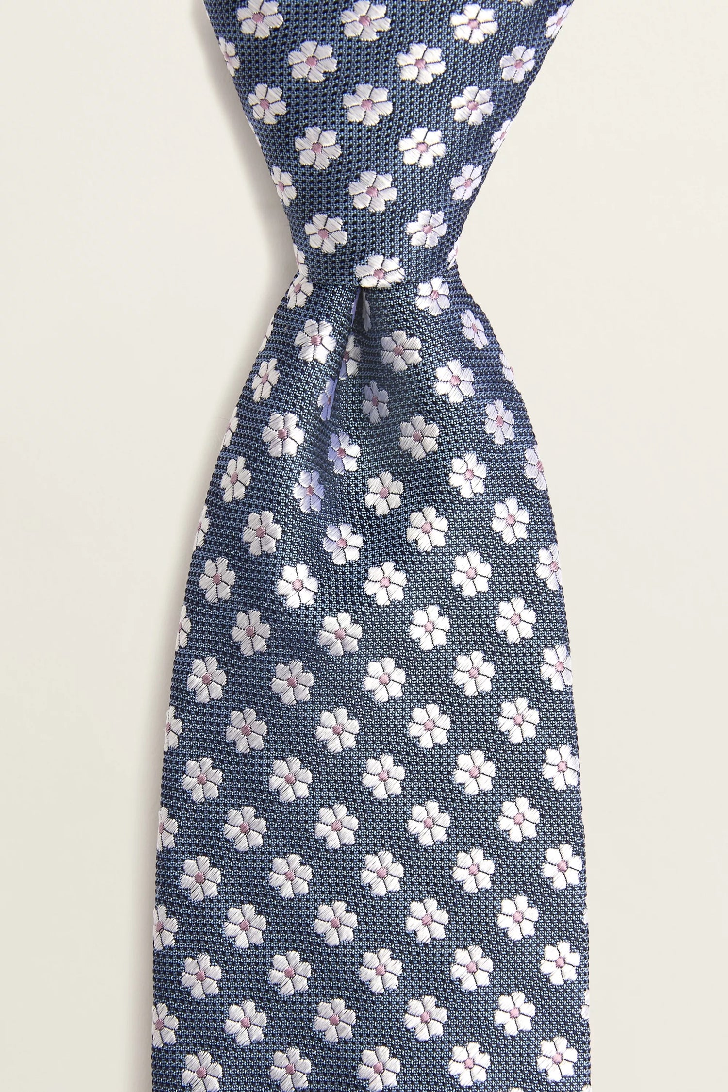 a tie with a blue background and a pattern of small white daisies